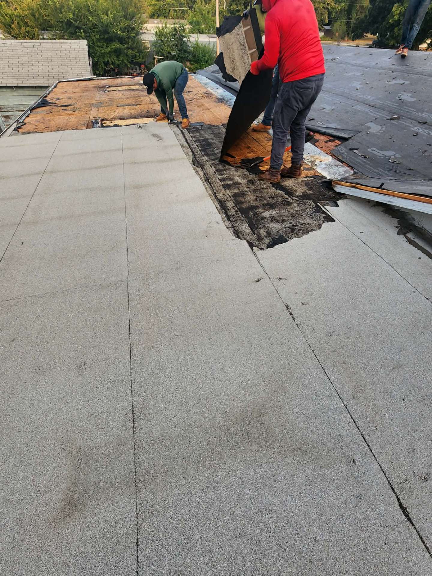 Crew installing modified bitumen membrane on flat roof