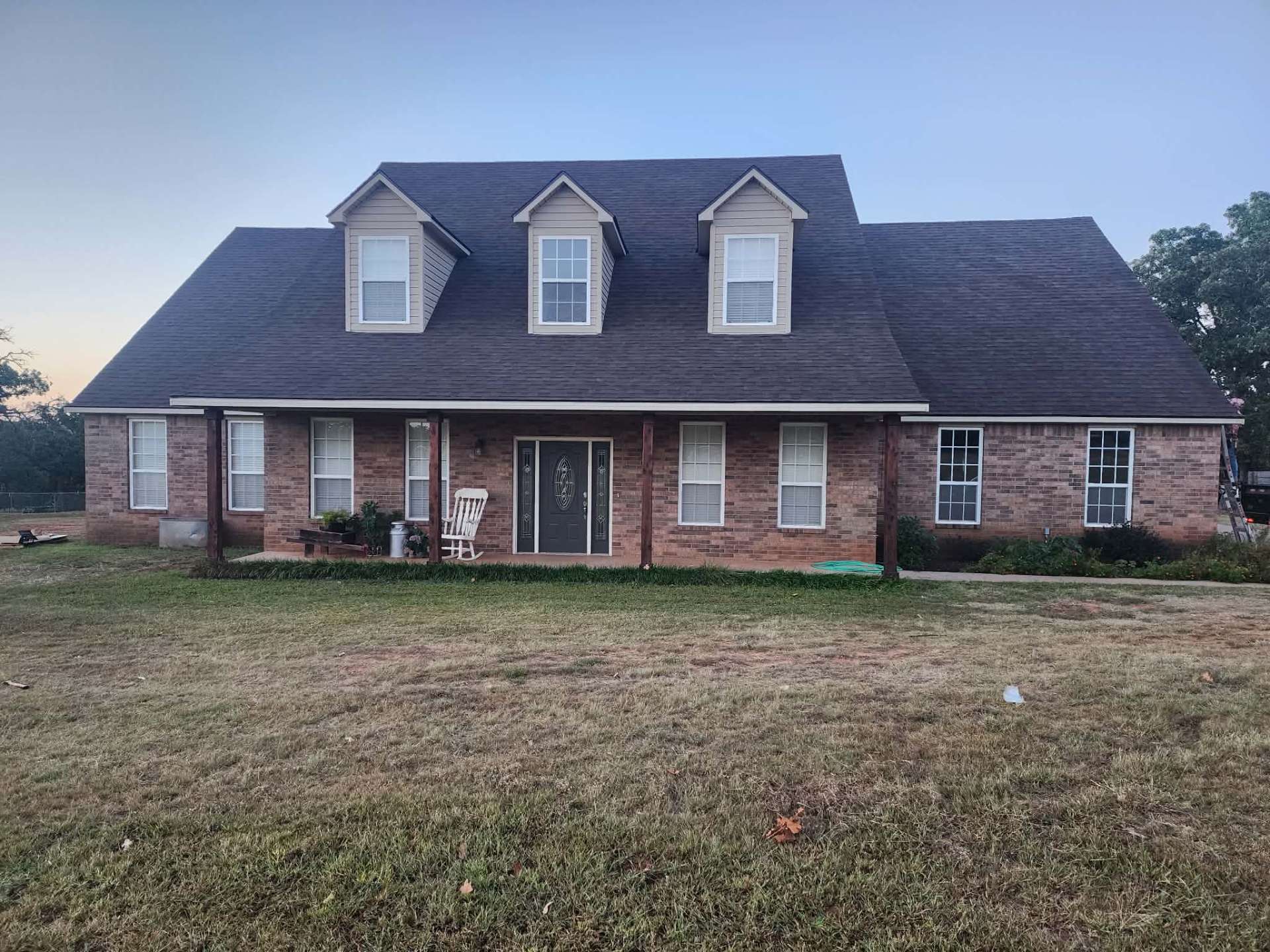Completed roof replacement on large brick Oklahoma home with three dormers