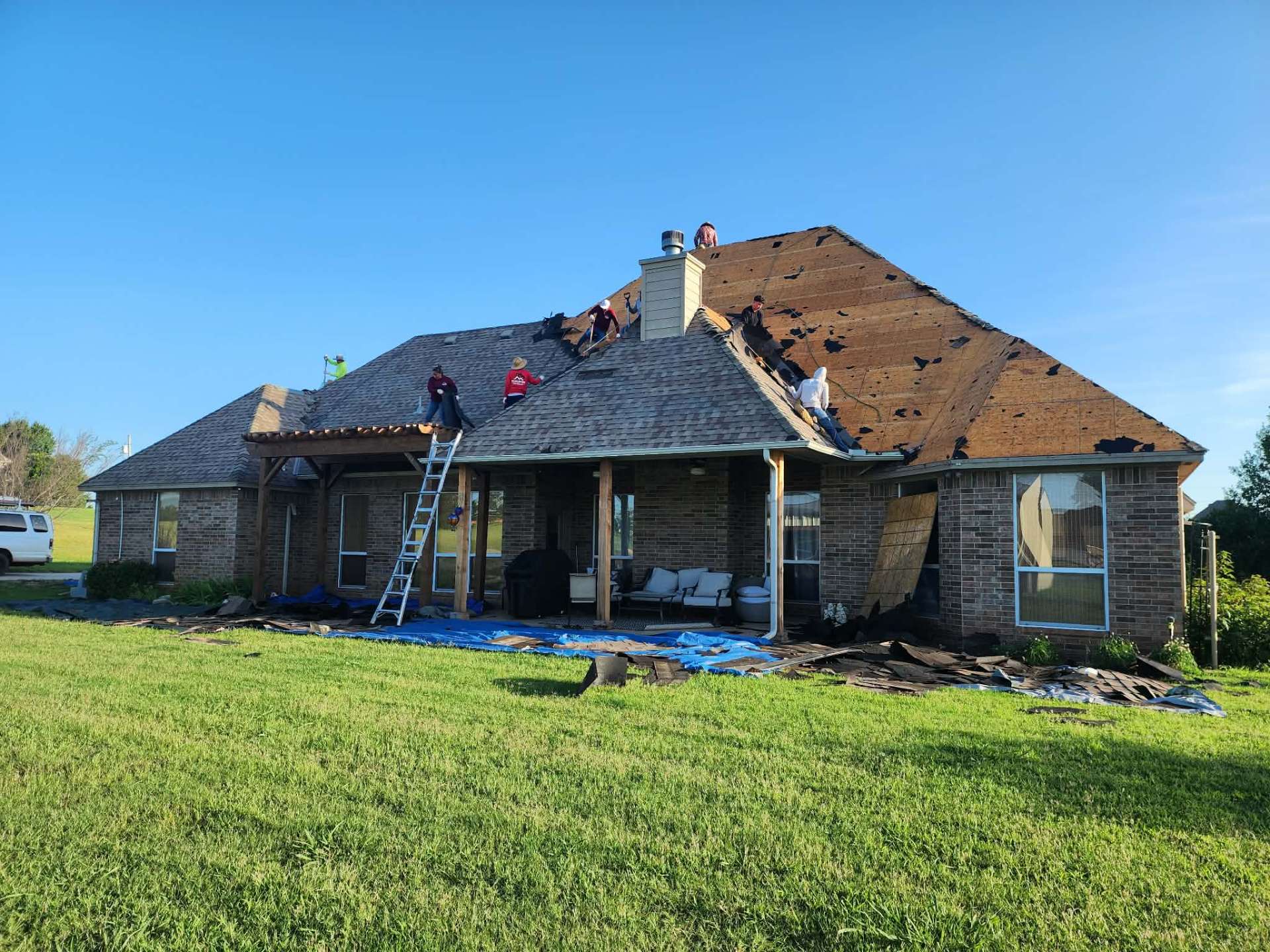 Full tear-off in progress — exposed decking on large hip roof