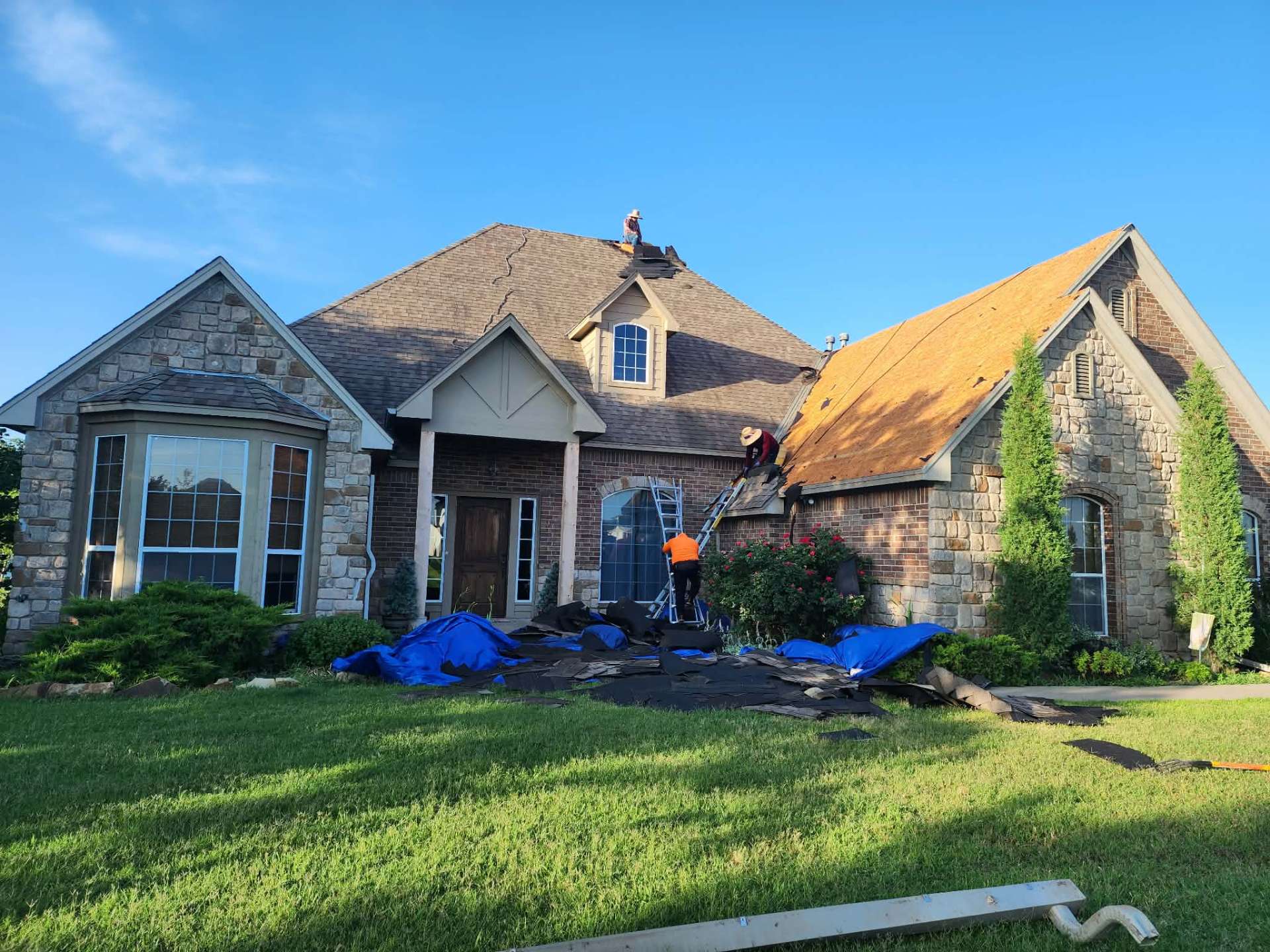 Front elevation tear-off with debris tarped over landscaping